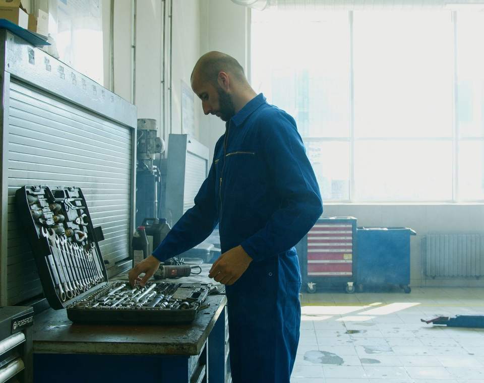 Technicien de maintenance en combinaison préparant ses outils sur un établi, atelier lumineux