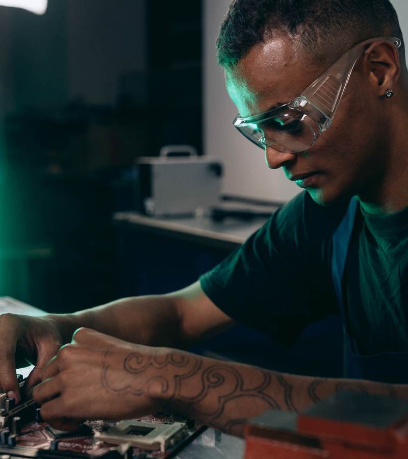 Technicien portant des lunettes de protection assemblant les composants d’une carte mère sur un établi