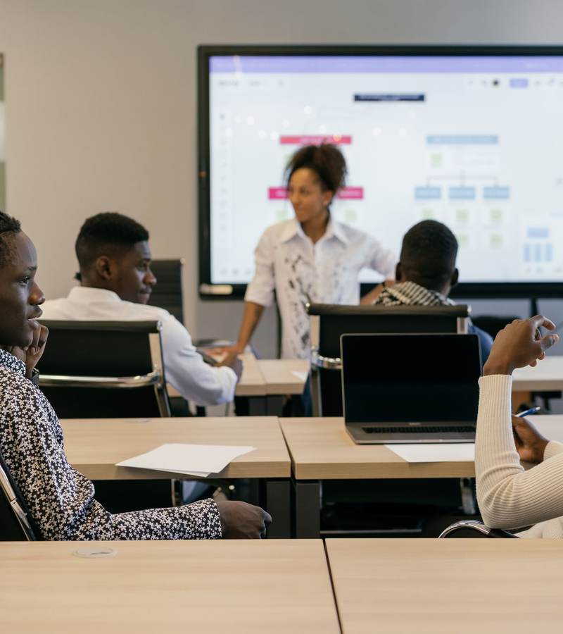 Formatrice présentant un schéma sur écran à des apprenants assis devant leurs ordinateurs